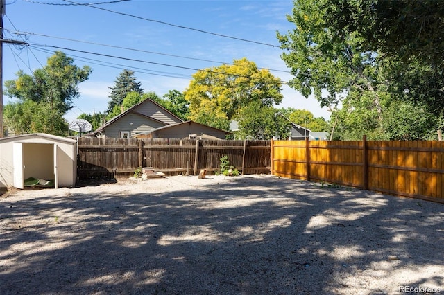 view of yard featuring an outdoor structure, a fenced backyard, and a storage shed