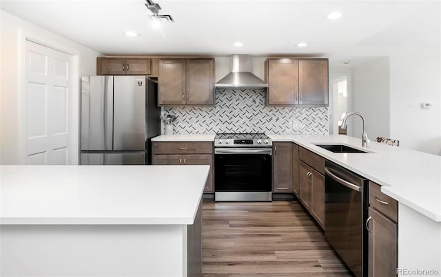 800 Pearl St Unit 1010, Denver, CO 80203 - kitchen featuring appliances with stainless steel finishes, wall chimney range hood, a peninsula, wood finished floors, and light countertops