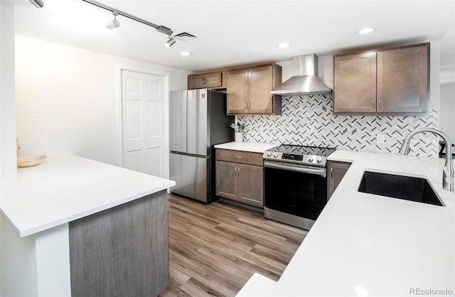 800 Pearl St Unit 1010, Denver, CO 80203 - kitchen featuring wall chimney exhaust hood, stainless steel appliances, light wood-type flooring, and light countertops