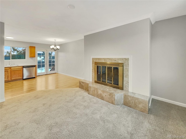 unfurnished living room featuring a fireplace, light hardwood / wood-style floors, a notable chandelier, and sink