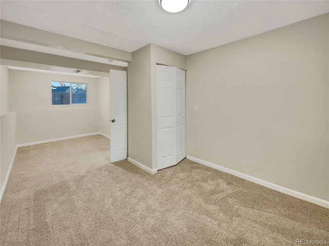 unfurnished bedroom featuring carpet flooring, a textured ceiling, and a closet