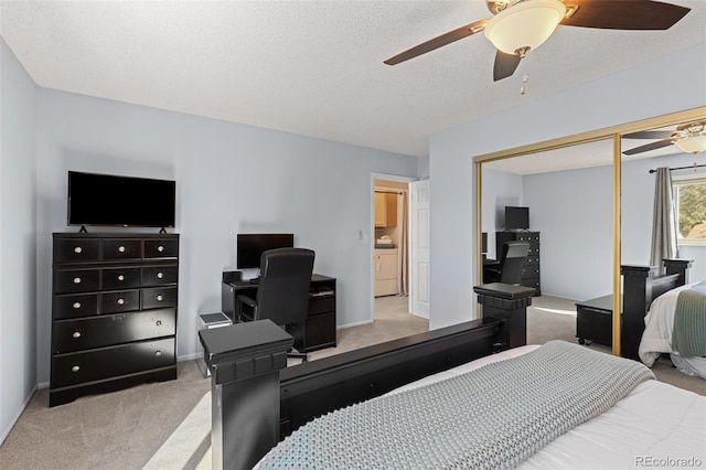 bedroom with ceiling fan, light colored carpet, washer / dryer, a closet, and a textured ceiling