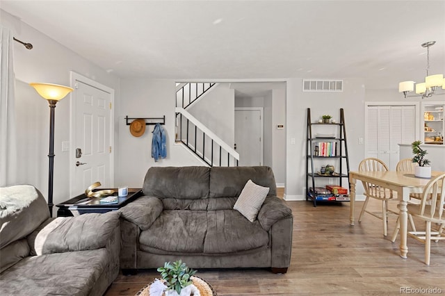 living room with wood finished floors, baseboards, visible vents, stairs, and a chandelier