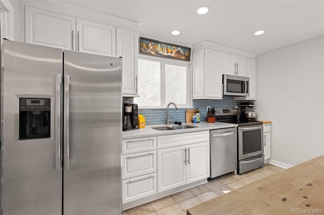 kitchen featuring backsplash, light countertops, stainless steel appliances, white cabinetry, and a sink