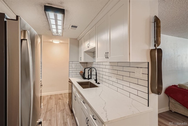 kitchen featuring white cabinets, light hardwood / wood-style floors, stainless steel appliances, and sink