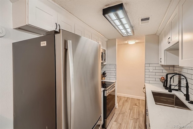 kitchen featuring white cabinets, stainless steel appliances, sink, and backsplash