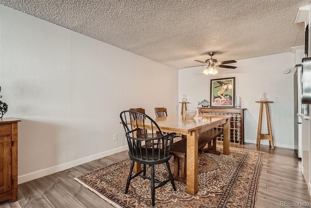 dining area featuring wood-type flooring, ceiling fan, and a textured ceiling