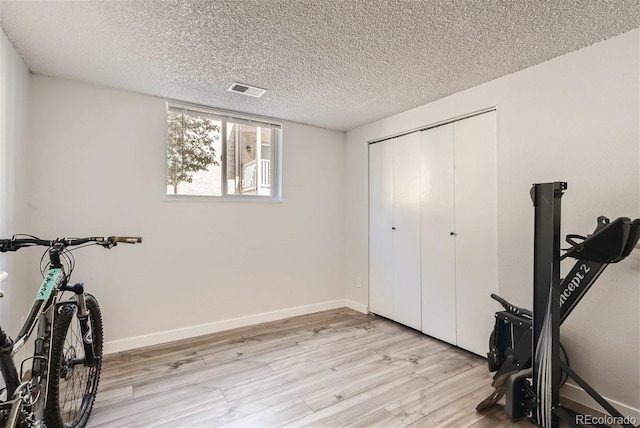 workout room with a textured ceiling and light hardwood / wood-style flooring