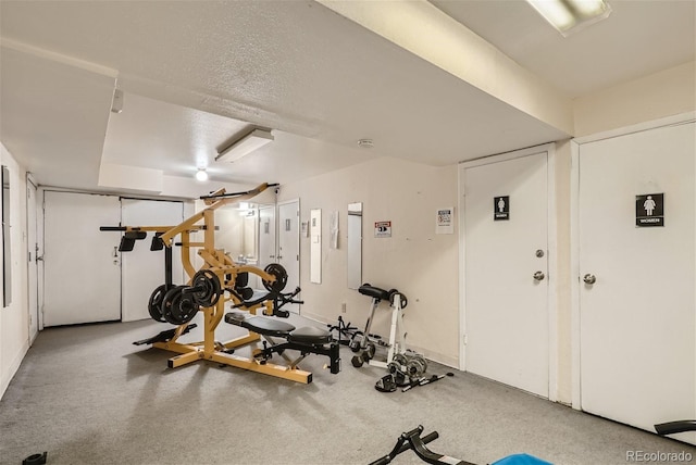 exercise room featuring a textured ceiling and carpet flooring