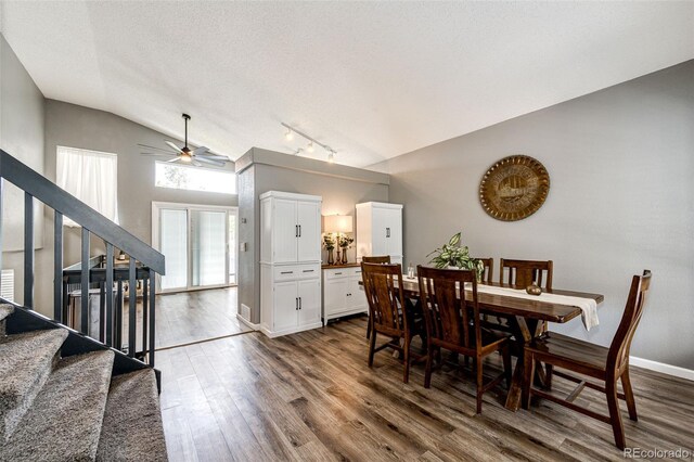 8930 Apache Plume Dr, Parker, CO 80134 - dining area featuring vaulted ceiling, stairway, ceiling fan, dark wood-style floors, and rail lighting