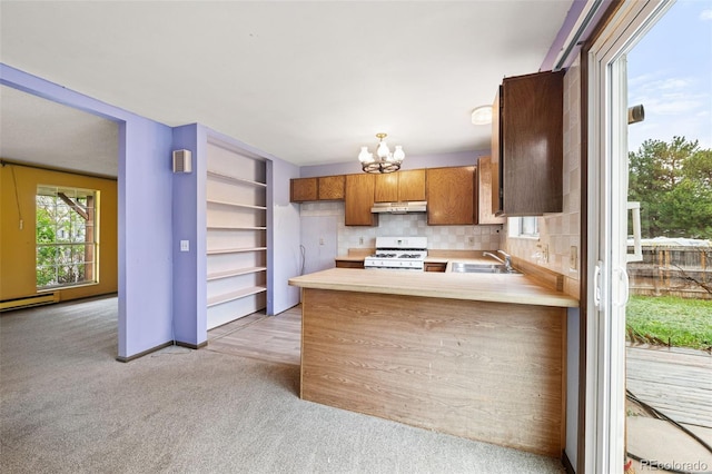 kitchen featuring white gas range oven, under cabinet range hood, light carpet, and light countertops