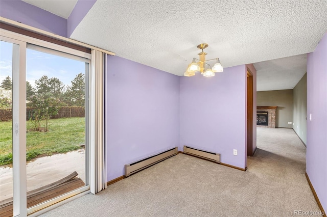 carpeted spare room featuring a baseboard radiator, a chandelier, a fireplace, baseboards, and a textured ceiling