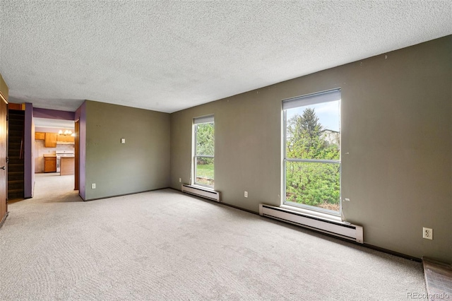 spare room featuring a baseboard heating unit, baseboard heating, carpet floors, a textured ceiling, and stairs