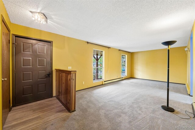 carpeted entrance foyer with a baseboard heating unit and a textured ceiling