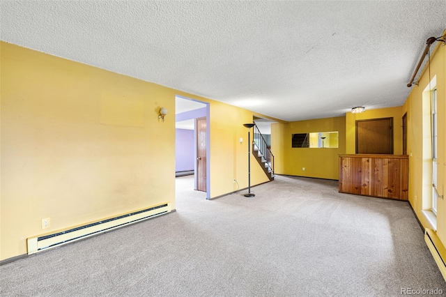 unfurnished room with baseboard heating, stairway, carpet, and a textured ceiling