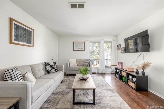 living area with visible vents, baseboards, and wood finished floors