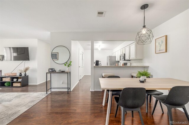 dining room featuring dark wood-style floors, visible vents, and baseboards