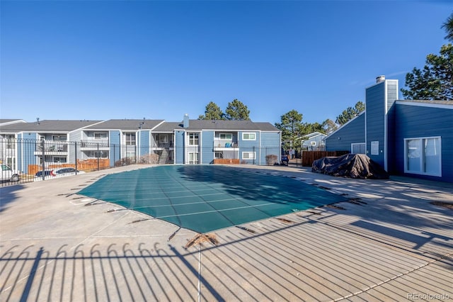 view of swimming pool featuring a fenced in pool, fence, a patio area, and a residential view