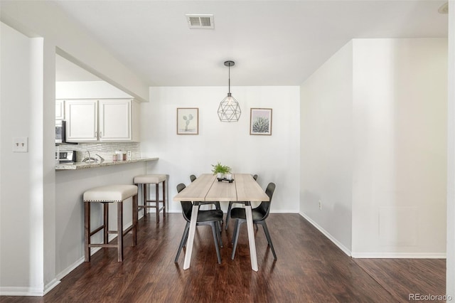 dining room featuring visible vents, baseboards, and dark wood-type flooring