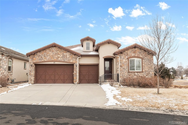 mediterranean / spanish home with concrete driveway, an attached garage, a tile roof, and stucco siding