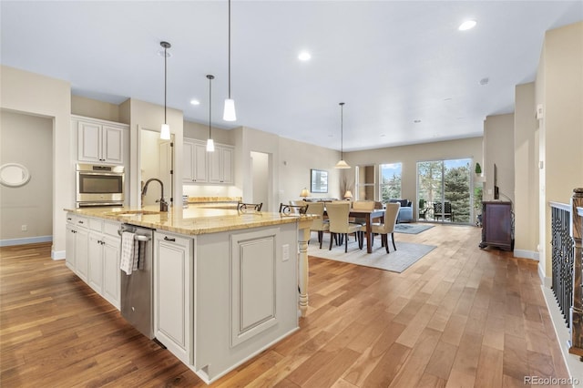 kitchen featuring open floor plan, a sink, light wood-style flooring, and white cabinetry