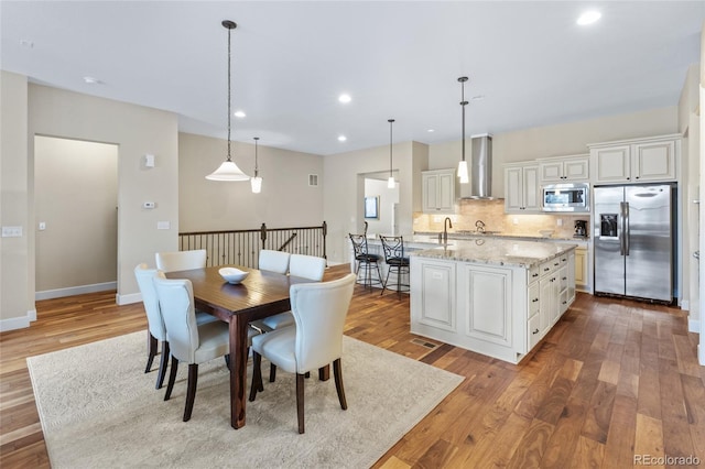 dining area featuring baseboards, wood finished floors, and recessed lighting