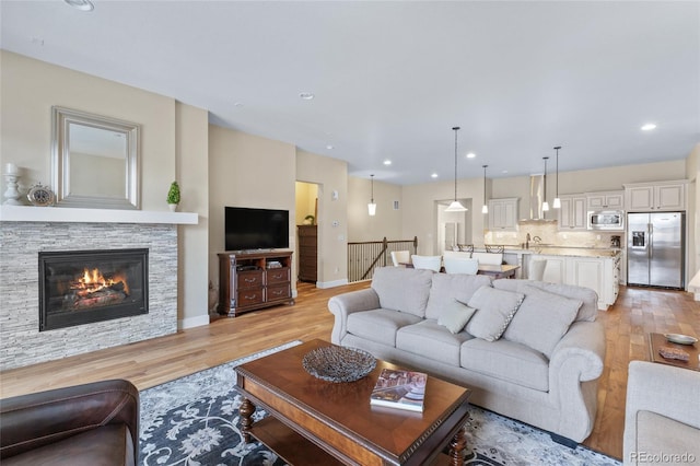 living area with light wood finished floors, a fireplace, baseboards, and recessed lighting