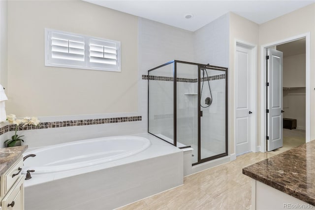 full bath with a walk in closet, a garden tub, a shower stall, and vanity