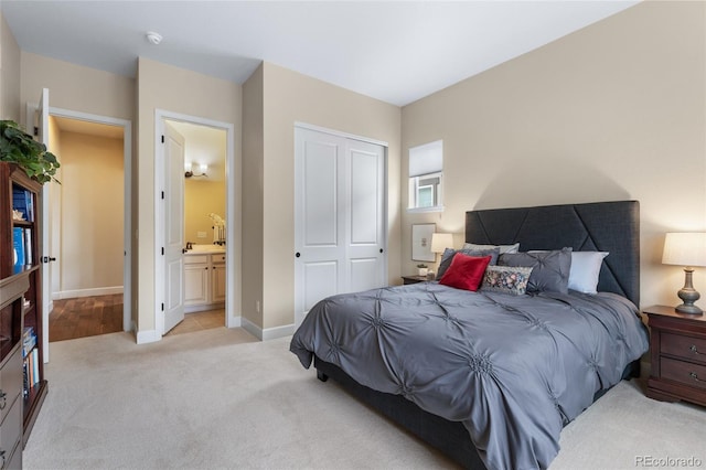 bedroom with light carpet, a closet, ensuite bathroom, and baseboards