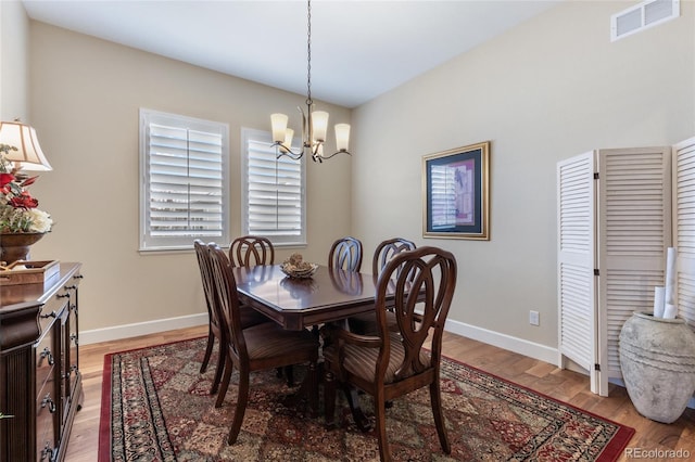 dining space with light wood-style floors, visible vents, a notable chandelier, and baseboards