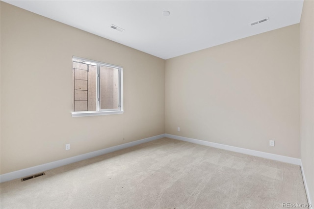 empty room featuring baseboards, visible vents, and light colored carpet