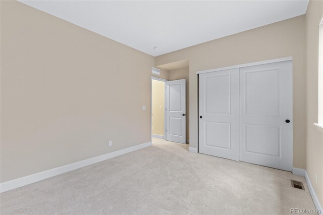 unfurnished bedroom featuring light carpet, visible vents, baseboards, and a closet