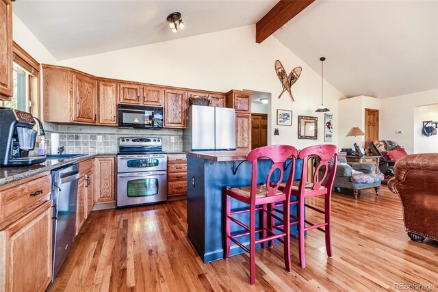 16 Thurber Ct, Fairplay, CO 80440 - kitchen with dark countertops, open floor plan, a kitchen bar, light wood-style floors, and stainless steel appliances