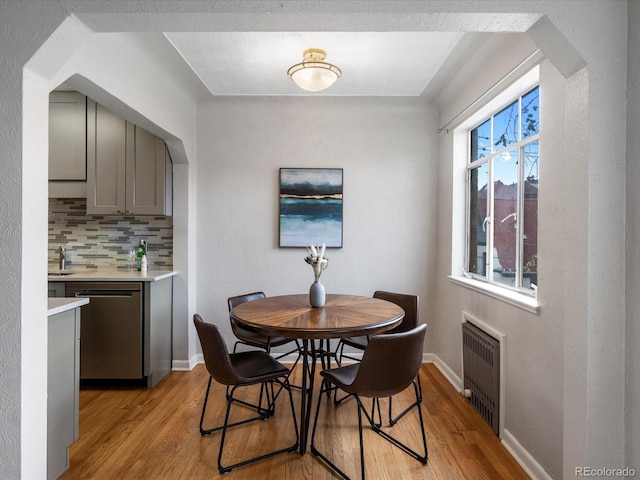 1130 N N Pennsylvania St Unit 306, Denver, CO 80203 - dining area with light wood finished floors, radiator heating unit, and arched walkways