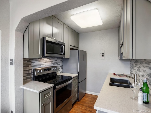 1130 N N Pennsylvania St Unit 306, Denver, CO 80203 - kitchen with stainless steel appliances, gray cabinets, decorative backsplash, and wood finished floors