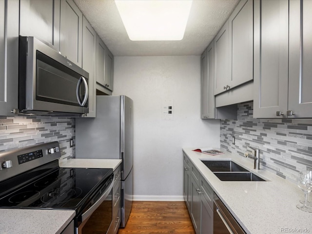 1130 N N Pennsylvania St Unit 306, Denver, CO 80203 - kitchen with stainless steel appliances, gray cabinetry, backsplash, dark wood finished floors, and a textured ceiling