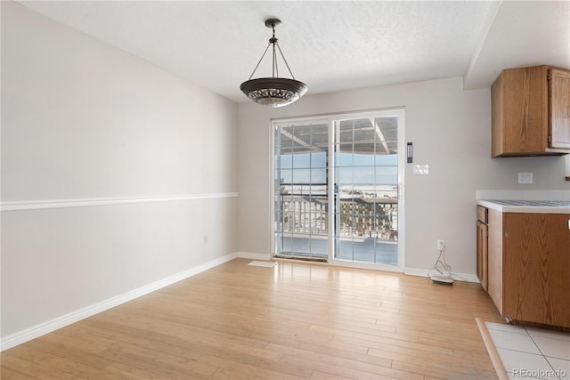 unfurnished dining area with light wood-type flooring and a textured ceiling