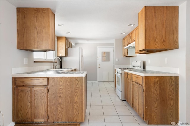 kitchen with light tile patterned floors, white appliances, tile counters, and sink