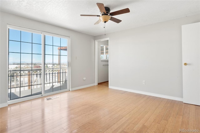 empty room with ceiling fan, a textured ceiling, and light wood-type flooring