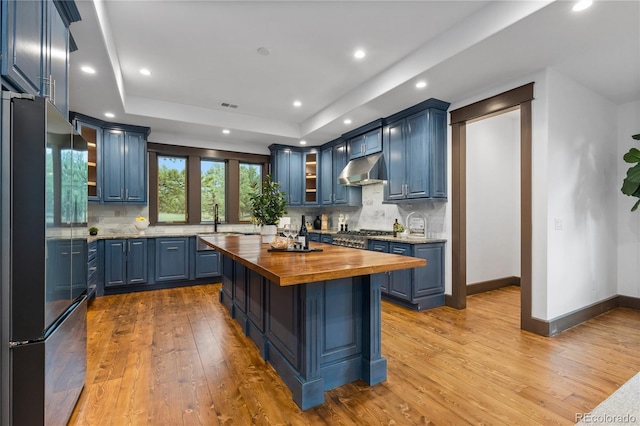 11790 Huckleberry Dr, Franktown, CO 80116 - kitchen with appliances with stainless steel finishes, wood counters, blue cabinetry, light wood finished floors, and recessed lighting