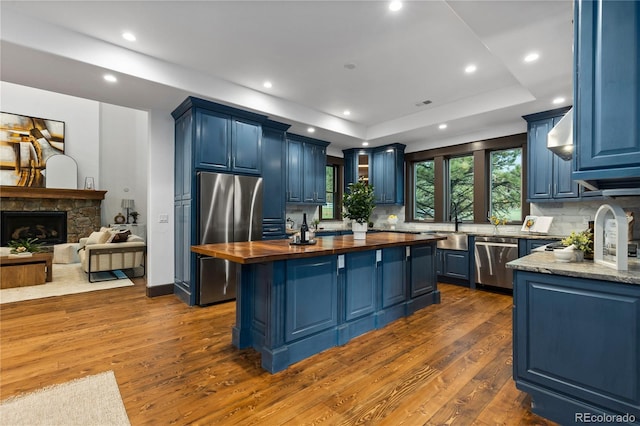 11790 Huckleberry Dr, Franktown, CO 80116 - kitchen with wood counters, stainless steel appliances, blue cabinetry, a raised ceiling, and recessed lighting