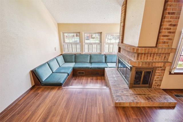10262 W Ida Ave Unit 243, Littleton, CO 80127 - unfurnished living room with wood finished floors, a brick fireplace, and a textured ceiling