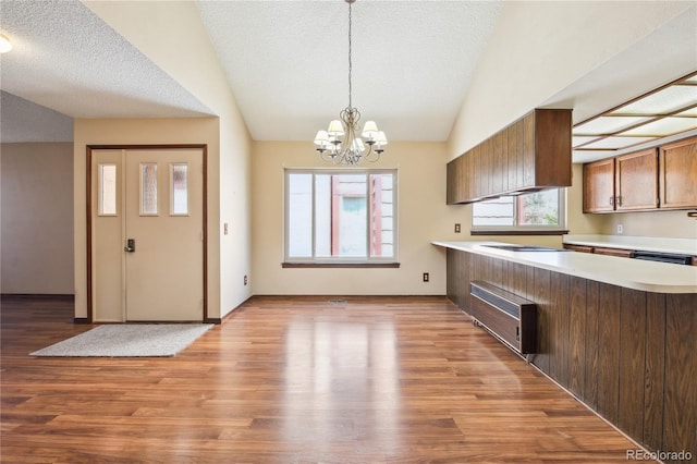 10262 W Ida Ave Unit 243, Littleton, CO 80127 - kitchen with light countertops, a chandelier, light wood-style flooring, a peninsula, and brown cabinetry