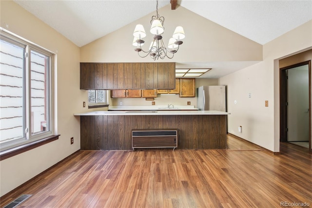 10262 W Ida Ave Unit 243, Littleton, CO 80127 - kitchen featuring a peninsula, light countertops, wood finished floors, freestanding refrigerator, and a chandelier
