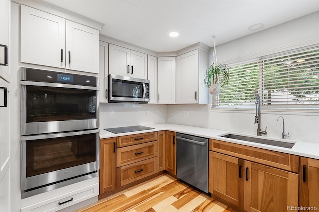 11313 Haswell Dr, Parker, CO 80134 - kitchen featuring appliances with stainless steel finishes, light wood finished floors, light countertops, white cabinets, and recessed lighting