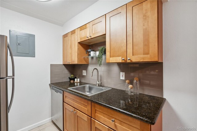 kitchen with electric panel, sink, backsplash, stainless steel appliances, and dark stone countertops