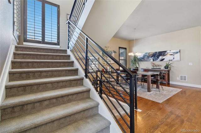 stairway with an inviting chandelier and wood-type flooring