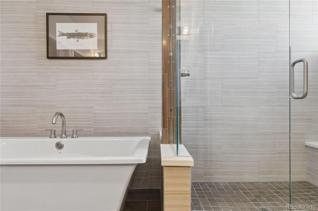 bathroom featuring tile walls and independent shower and bath