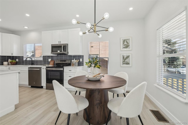 dining space featuring sink, an inviting chandelier, and light hardwood / wood-style floors