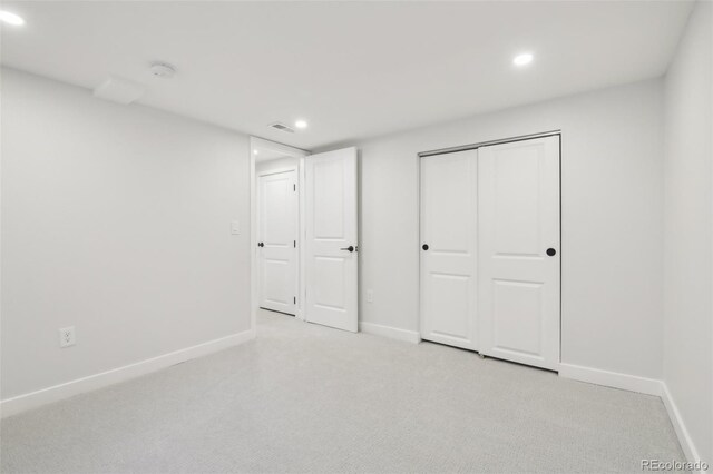 unfurnished bedroom featuring light colored carpet and a closet